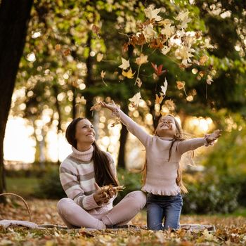 Mother and daughter enjoying autumn in park.