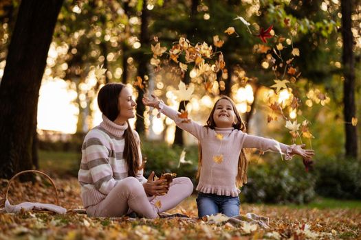 Mother and daughter enjoying autumn in park.