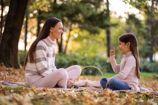 Mother and daughter enjoying autumn in park.