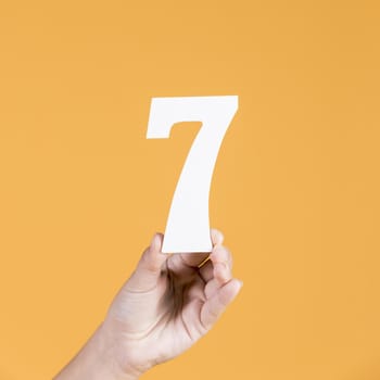 human hand holding number seven against yellow background. Resolution and high quality beautiful photo