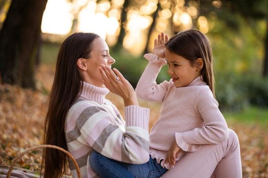 Mother and daughter enjoying autumn in park.