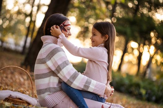 Mother and daughter enjoying autumn in park.