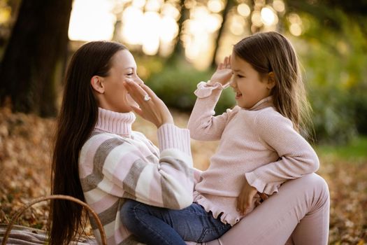 Mother and daughter enjoying autumn in park.