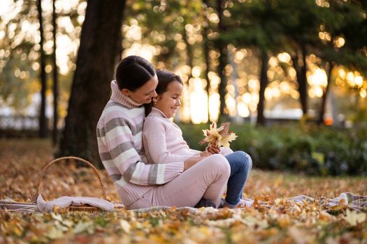 Mother and daughter enjoying autumn in park.