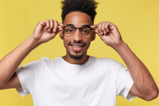 Headshot of good-looking positive young dark-skinned male with stubble and trendy haircut wearing white shirt while posing isolated against blank studio wall background with copy space for your text.