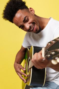 african american retro styled guitarist playing acoustic guitar isolated on yellow gold background.