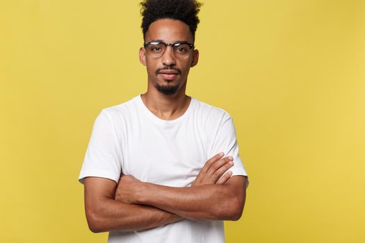 Close up portrait of a happy african american man posing with arms crossed on isolated yellow background.