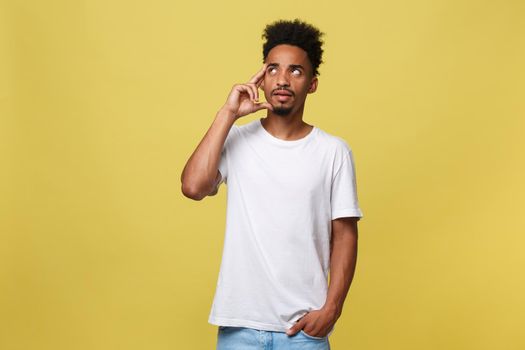 Image of thoughtful young african man dressed in white tshirt standing isolated over yellow background