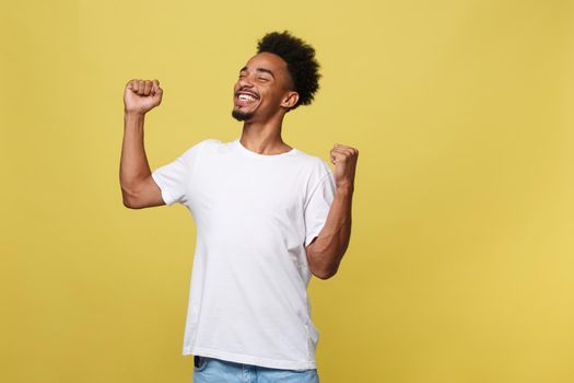 Portrait of a cheerful young man shouting with arms raised in success.