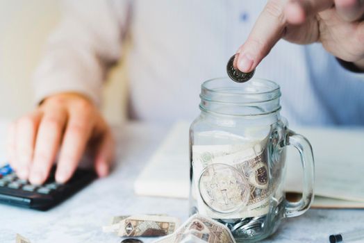 hand putting coin inside jar. Beautiful photo