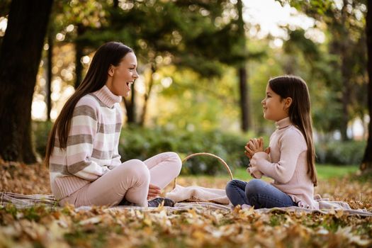 Mother and daughter enjoying autumn in park.