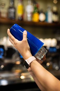 hand of woman with shaker preparing coktail at the bar