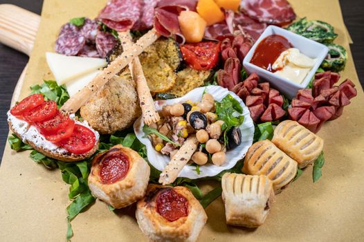 mixed antipasto platter with cold cuts and legumes and cheeses and sauces and snacks