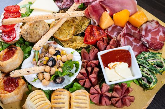 mixed antipasto platter with cold cuts and legumes and cheeses and sauces and snacks