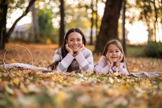 Mother and daughter enjoying autumn in park.