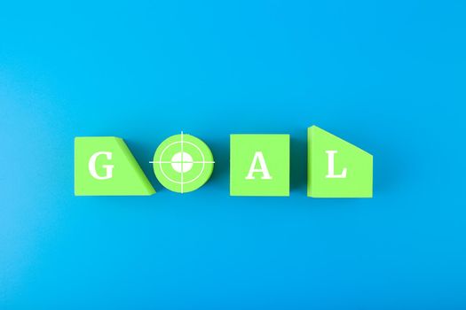 Goal single word written on green geometric figures in a row in the middle of blue background. Concept of goal, success, reaching business and personal aims