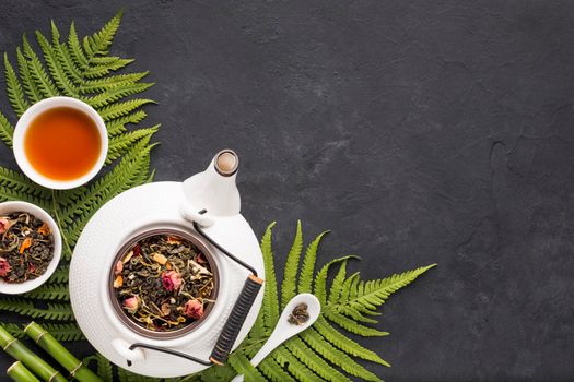 dried tea herb with fern leaves bamboo stick black textured backdrop. High resolution photo