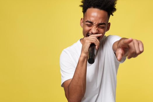 Stylish afro american man singing into microphone isolated on a yellow gold background.