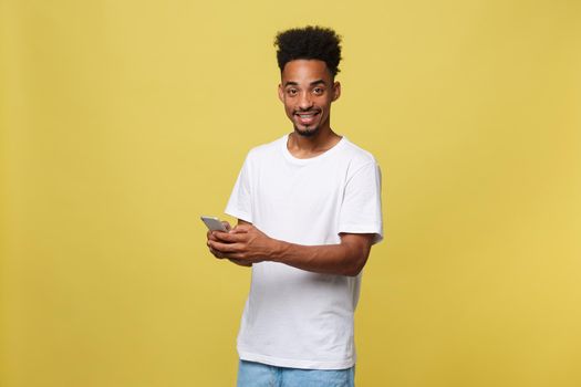 Happy african american man with smiling and using mobile phone. Isolated on yellow background