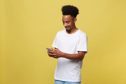 Happy african american man with smiling and using mobile phone. Isolated on yellow background