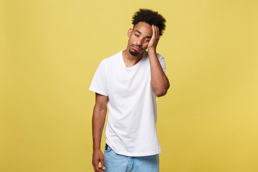 Portrait of attractive sleepy african-american male model in trendy black hat, yawning, covering mouth with palm and stretching, feeling tired and sleepy over yellow background.