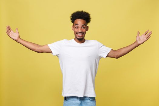 Advertising concept. Portrait of handsome African entrepreneur or office worker wearing suit pointing his finger at yellow studio wall with copy space for your content, looking shocked and surprised