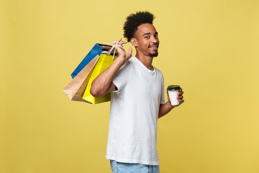 African American man with colorful paper bags isolated on yellow background.