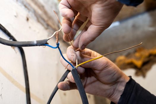 An electrician twists electrical wires in a house under construction to conduct electricity.