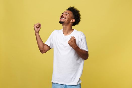 Portrait of a cheerful young man shouting with arms raised in success.