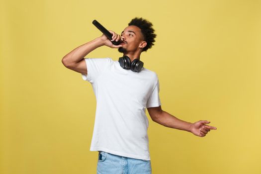 Young handsome African American Male Singer Performing with Microphone. Isolated over yellow gold background