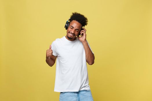 Portrait good-looking african male model with beard listening to music. Isolated over yellow background.