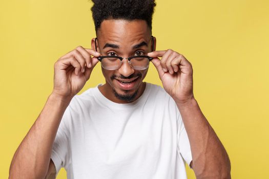 Headshot of good-looking positive young dark-skinned male with stubble and trendy haircut wearing white shirt while posing isolated against blank studio wall background with copy space for your text.