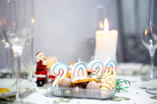 Christmas table with utensils and glasses, a table with burning candles, in a dark room