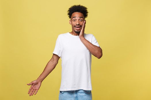 Advertising concept. Portrait of handsome African entrepreneur or office worker wearing suit pointing his finger at yellow studio wall with copy space for your content, looking shocked and surprised