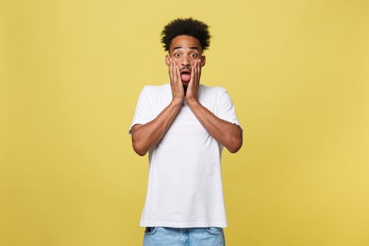 Emotional and People Concept - Portrait of excited young African American man screaming in shock and amazement holding hands on head