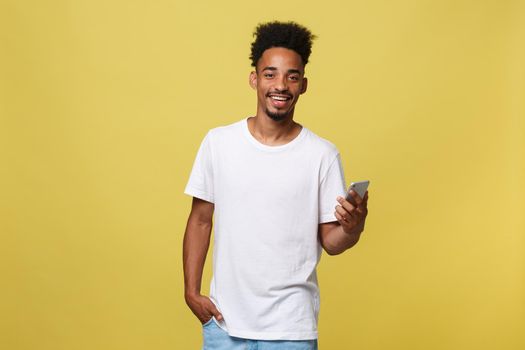 Happy african american man with smiling and using mobile phone. Isolated on yellow background