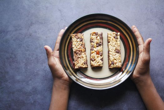 Almond , Raisin and oat protein bars on black background .,