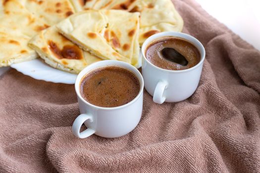 Homemade freshly baked flat bread stuffed with cottage cheese on a table with two mugs of coffee