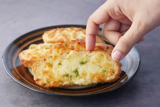 hand pick a garlic bread on a plate .