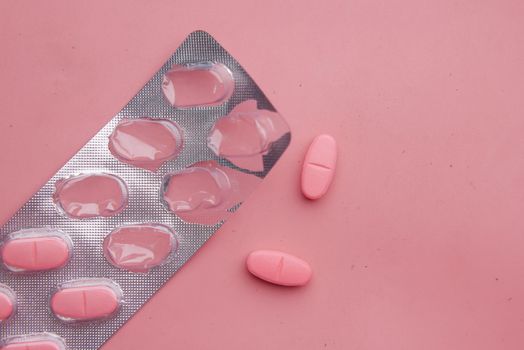 pink color medical pills spilling on pink .