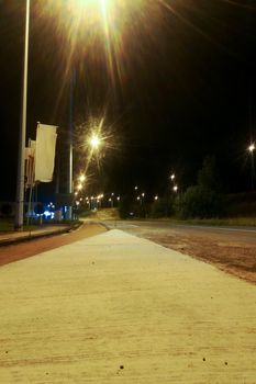 Empty road at night with citylights and flags