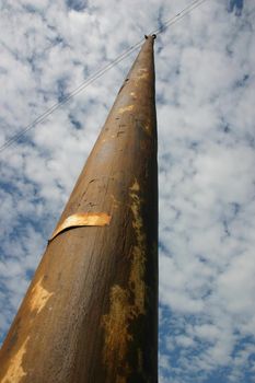 Image of A large old telephone pole stretches up into a cloudy sky
