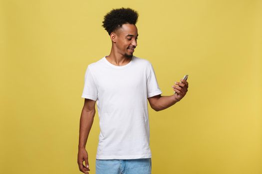 Happy african american man with smiling and using mobile phone. Isolated on yellow background