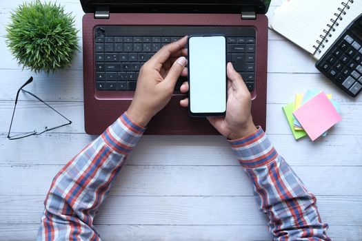 top view of man hand using smart phone on office desk.