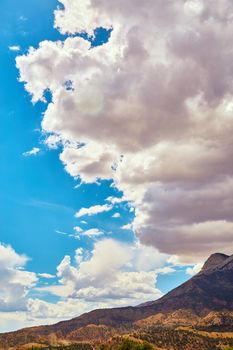 Image of Looming clouds over desert mountains against blue sky