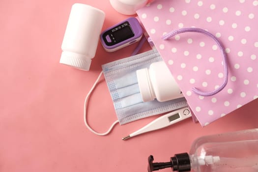 Surgical masks, thermometer and hand sanitizer on orange background .