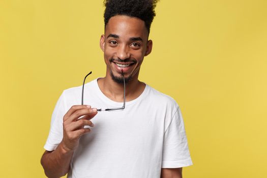 Headshot of good-looking positive young dark-skinned male with stubble and trendy haircut wearing white shirt while posing isolated against blank studio wall background with copy space for your text.