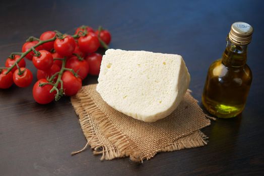 cherry tomato, cheese and olive oil on table .