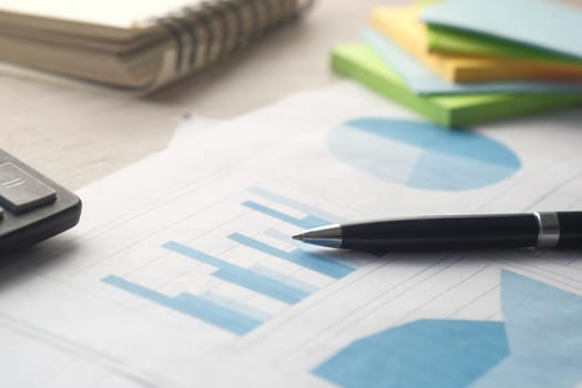 financial graph, calculator and notepad on table.