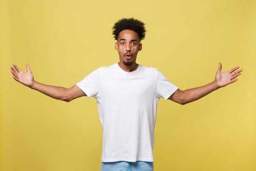 Advertising concept. Portrait of handsome African entrepreneur or office worker wearing suit pointing his finger at yellow studio wall with copy space for your content, looking shocked and surprised